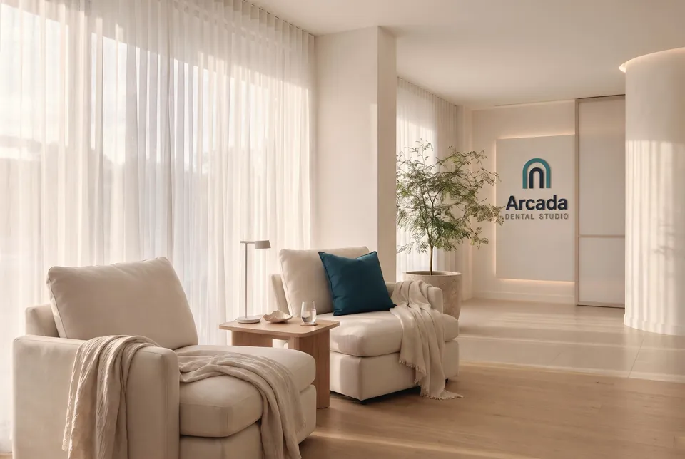 A calm recovery lounge with soft chairs, sheer curtains and a teal cushion.